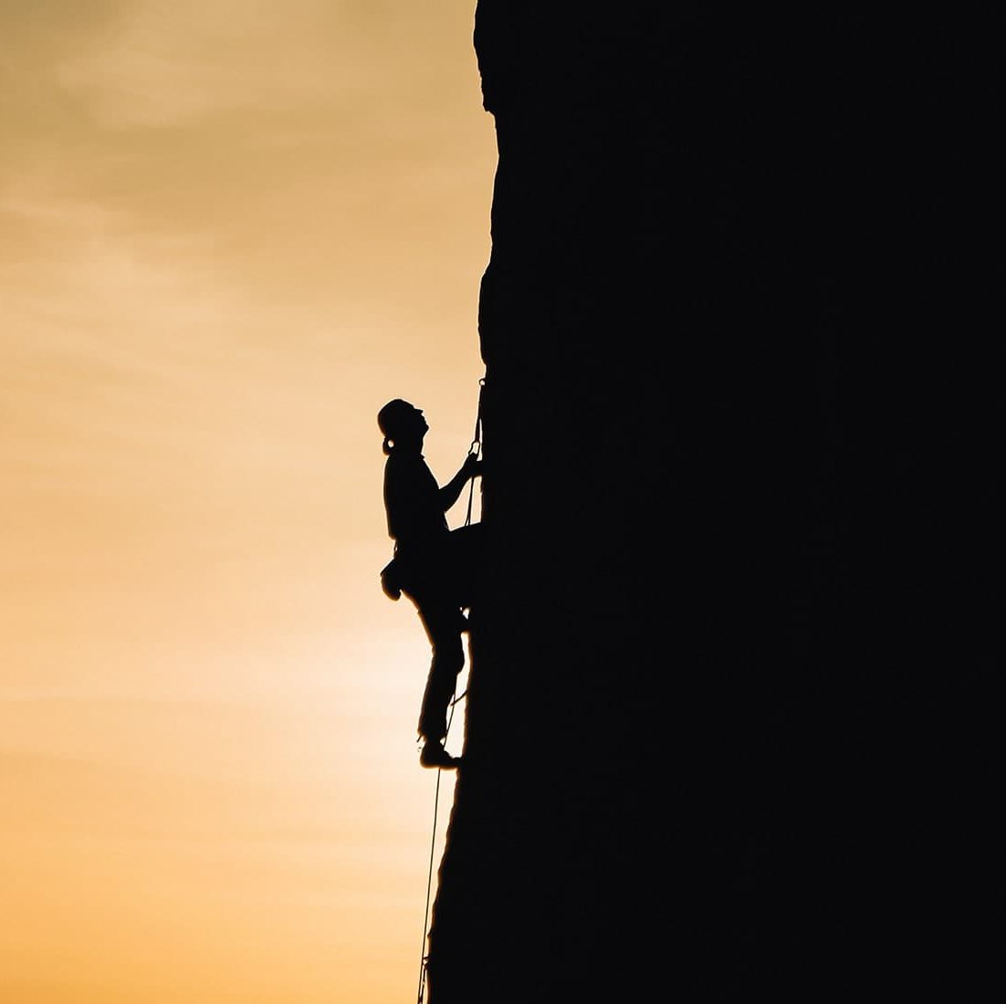 A woman rock climbing at sunset